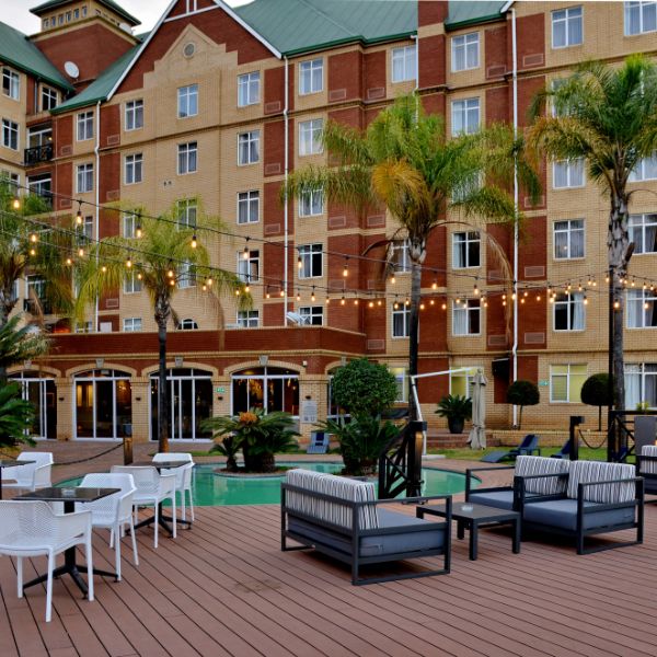 Photo of ANEW's Capital Hotel in Pretoria, displaying their luxurious pool area furnished with outdoor couches, tables and chairs.