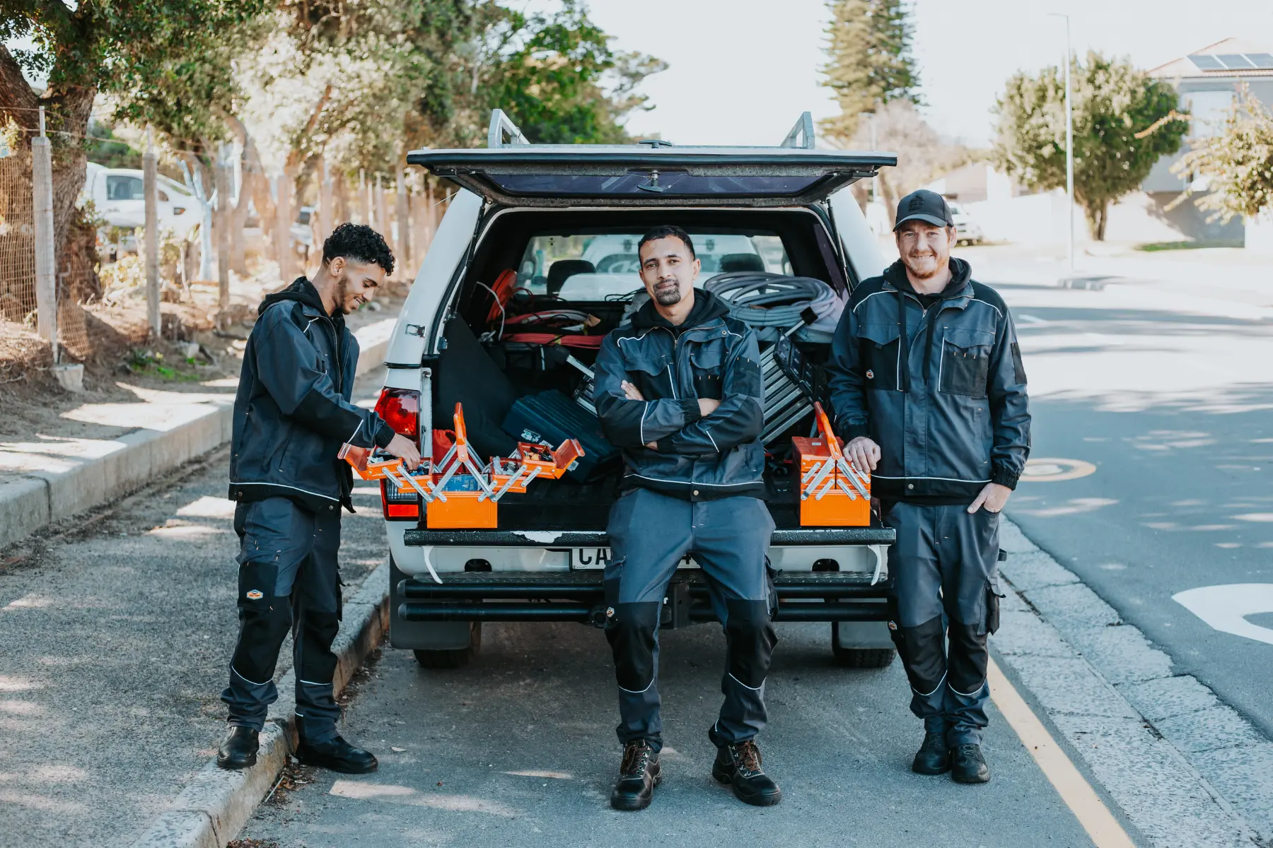 Photo of three COC electricians at the back of a truck getting tools together.